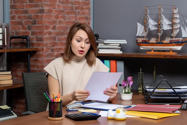A person sitting at a desk reviewing documents related to student loan forgiveness programs, with a calculator and pen nearby, symbolizing the careful consideration and planning required to apply. The desk includes a laptop displaying a government website about student loans.