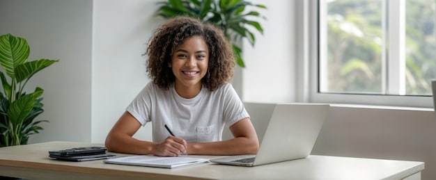 A student sitting at a desk, smiling while filling out the FAFSA form on a laptop. A calculator and textbook are visible on the desk.