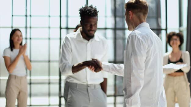 A person confidently extending their hand for a handshake, symbolizing the act of making a connection with a potential mentor. The background shows an office setting with people collaborating.