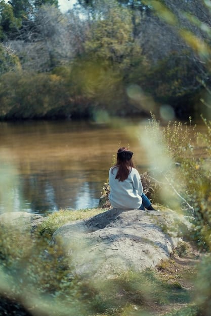 A person meditating in a peaceful setting, surrounded by nature, with a serene expression, symbolizing self-compassion and inner peace.