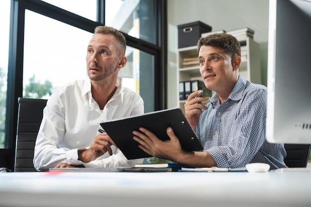 Two professionals sitting across a table, engaged in a thoughtful discussion during a performance review. One is actively listening and taking notes, while the other is speaking with a calm and confident demeanor. The setting is a well-lit office with a supportive atmosphere.