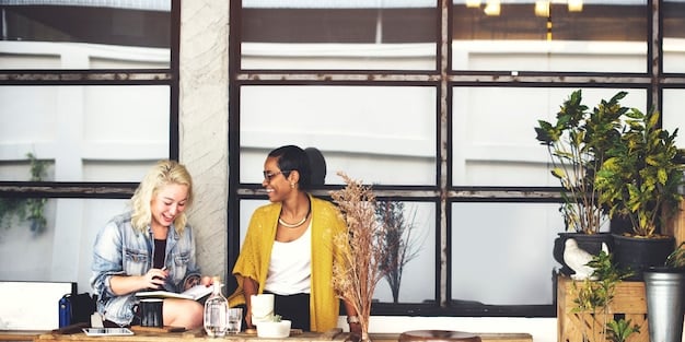 A diverse group of professionals collaborating around a table, discussing project ideas and sharing knowledge in a bright, modern office setting.