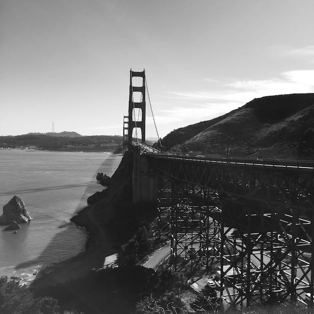A black-and-white photo of Alcatraz Island in San Francisco Bay, showing the infamous former prison, with the San Francisco skyline visible in the background.