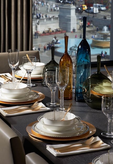 A well-set table in a restaurant, highlighting the arrangement of utensils, plates, and glasses. The ambiance is elegant, suggesting a fine dining experience.