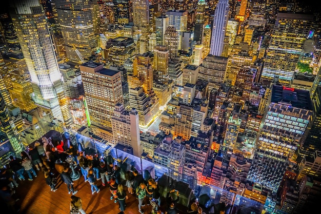 A panoramic view of Times Square in New York City during the New Year's Eve ball drop, with thousands of people gathered below, illuminated by the bright lights and excitement of the event.