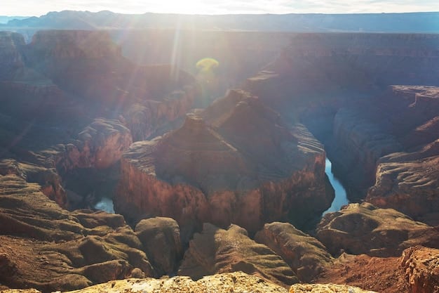 A scenic view of the Grand Canyon National Park, capturing the vastness of the canyon with layers of colorful rock formations under a clear blue sky. A small group of hikers can be seen in the distance, adding scale to the landscape.