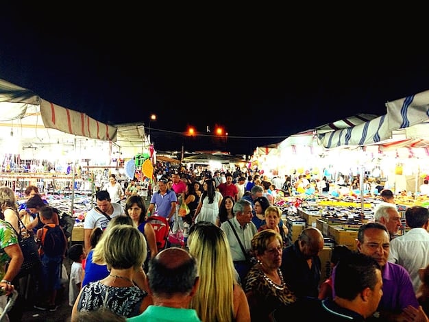 A bustling street festival in New Orleans, with colorful decorations, people dancing to live music, and vendors selling local crafts and food. The atmosphere is energetic and festive.