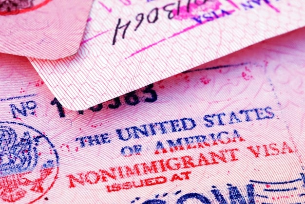 A close-up shot of a US passport with visa stamps, slightly blurred in the background. The focus is on the passport, symbolizing international travel and eligibility for the FEIE.