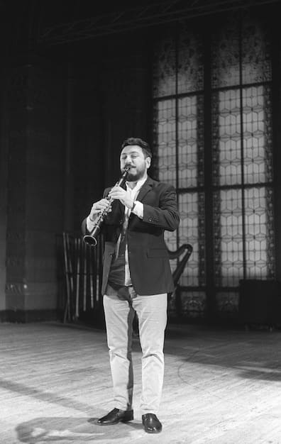 A vintage black and white photo of a vaudeville performance on a stage. Comedians are performing physical comedy, with exaggerated gestures and expressions. The audience is visible in the foreground, laughing heartily.